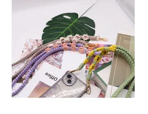 Detailed view of colorful handmade woven daisy phone straps with golden metal hooks on books
