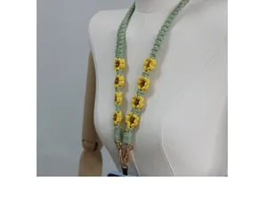 Macro view of hand-woven daisy lanyard with green rope and gold clasps