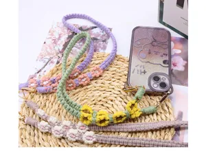Close-up of handmade woven flower phone straps with daisy patterns on a straw mat