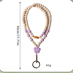 Detail van handgemaakte houten en siliconen kralen lanyard met paarse bloem en ring.