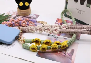 Detail view of colorful hand-woven daisy patterned phone lanyards with golden lobster clasps.