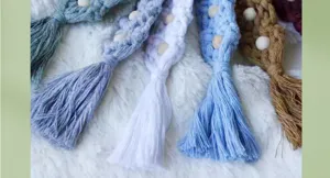 Détail de porte-clés en macramé fait main avec des perles en bois naturel et pompons en coton.