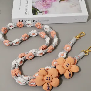 Detailaufnahme des bohemian gewebten Gänseblümchen Handybandes mit Stoffblume und Clips.
