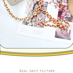 Detailed view of handmade floral braided strap for phones and bags in vibrant orange.