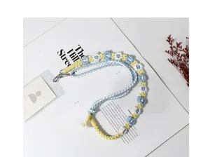 Detailed view of bohemian woven daisy flower lanyard with metal clasps on a stylish magazine