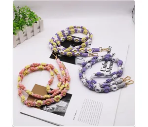 Hand-woven macramé daisy flower phone lanyards with gold lobster clasps on magazine background