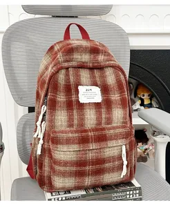 Close-up of a retro plaid backpack with red handle and front pocket, casual autumn style.