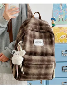 Retro brown plaid backpack detail, cozy winter tweed fabric with cute plush bear keychain charm.