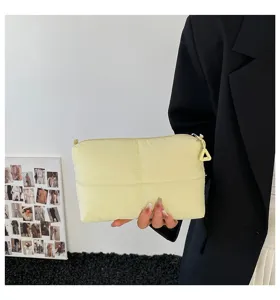 Nahaufnahme einer weichen, gesteppten gelben Kosmetiktasche, gehalten von einer Person
