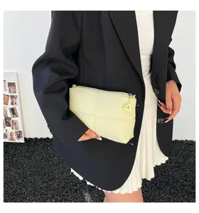 Detailansicht einer weichen gelben gesteppten Kosmetiktasche für Reisen, von Model gehalten