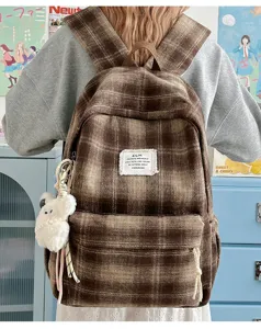 Retro plaid furry backpack detail showcasing brown tartan pattern and cute plush bear pendant.