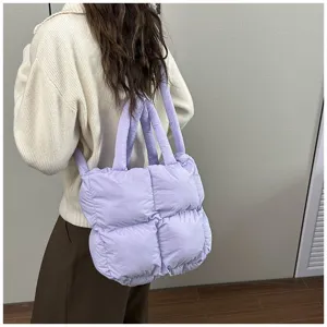 Detail of a light purple quilted puffer tote bag worn by a model in a casual setting.