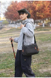 Model trägt eine große karierte Kuriertasche in einer herbstlichen Außenumgebung