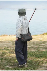 Outdoor-Lifestyle-Ansicht eines Mannes mit einer großen schwarzen gemusterten Umhängetasche