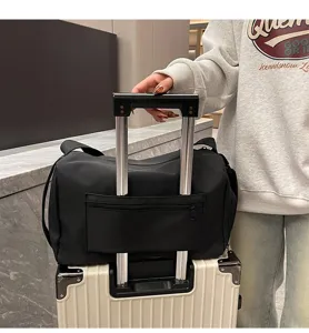 Detalle de bolsa de viaje negra con funda para maleta colocada sobre el asa del troley