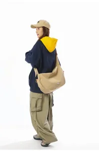 Asian model styling a large khaki dumpling messenger bag for casual travel