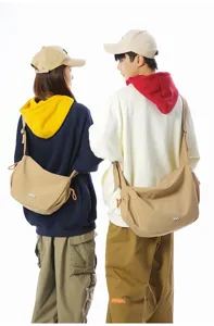 Rear view of couple wearing stylish khaki crossbody dumpling bags for travel