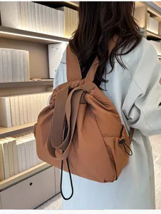 Detail view of brown nylon casual backpack showing adjustable drawstring and durable shoulder straps.