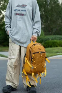 Large capacity yellow hiking backpack held by a model in an outdoor setting for travel.