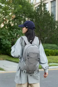 Rear view of a female model wearing a grey large capacity hiking backpack outdoors.