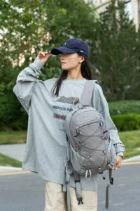 Asian female model carrying a gray lightweight hiking backpack in outdoor park setting