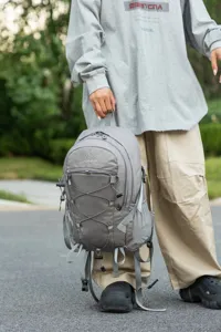 Person holding a grey lightweight outdoor hiking backpack in a natural outdoor setting