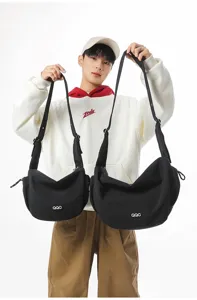 Male model holding two black minimalist crossbody dumpling bags in different sizes