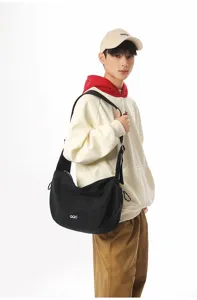 Large black dumpling messenger bag shown on model for casual and athletic commuting