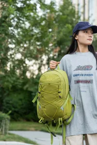 Large capacity lightweight green outdoor hiking backpack held by a traveler in a nature setting