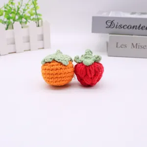 Handgehäkelte Obst-Anhänger aus Garn im Persimone- und Erdbeeren-Design.