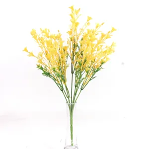 Détail de bouquet de fleurs jaunes artificielles, fausse tige florale avec feuilles vertes.