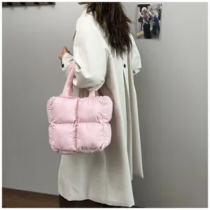 Fashionable pink puffer tote bag with quilted padding shown on model in trench coat