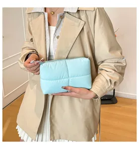 Weiche gesteppte Puffer-Kosmetiktasche in Hellblau, von einem Modell präsentiert