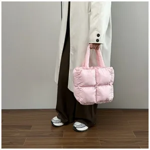 Stylish pink quilted puffer tote bag held by a model wearing a chic beige coat