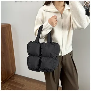 Detailed macro shot of a black quilted puffer tote bag carried by an elegant woman