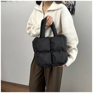 Black quilted padded tote bag shown in a lifestyle street fashion shot