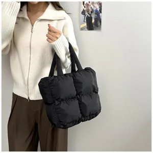 Puffy black quilted tote bag held by a model in a minimalist lifestyle view setting