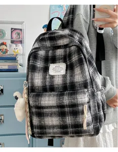 Detailed view of the vintage black and white plaid backpack showing front pocket and fabric label.
