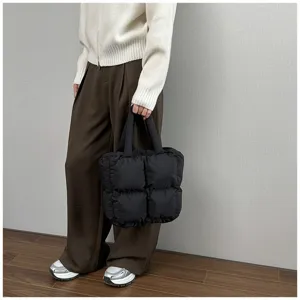 Close-up detail of a large black quilted puffer tote bag styled with a casual winter outfit