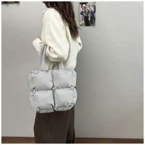 Model carrying a light grey puffy quilted tote bag over the shoulder in a casual setting