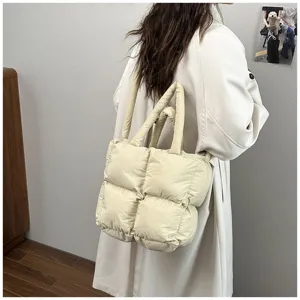 Detailed view of the cream quilted puffer tote bag on model shoulder for winter.