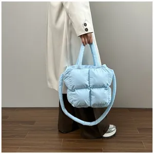 Light blue quilted puffer tote bag held by model against a minimalist background