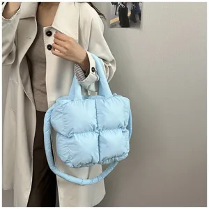 Light blue quilted puffer tote bag styled with a beige trench coat for a minimalist look
