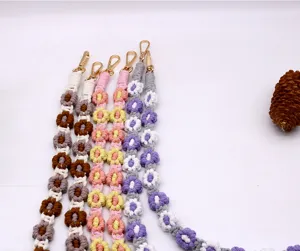 Detail of handmade bohemian woven daisy flower phone lanyards in colorful patterns
