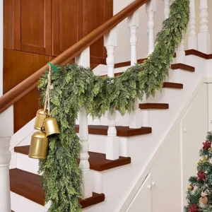 Artificial cedar pine garland with vintage gold bells draped on a wooden staircase