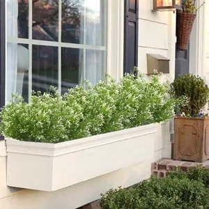 Detail view of artificial white flowers in a white outdoor window box planter.