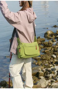Outdoor-Detail einer großen grün karierten Umhängetasche, getragen von einem Model.