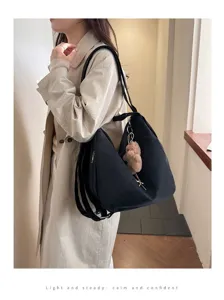 Large capacity black multi-functional bag worn by model in a stylish trench coat