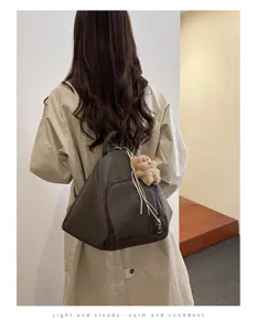 Minimalist brown triangular backpack for women with bear charm shown worn by model