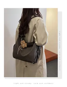 Large capacity charcoal brown hobo bag with teddy bear charm shown on model from behind